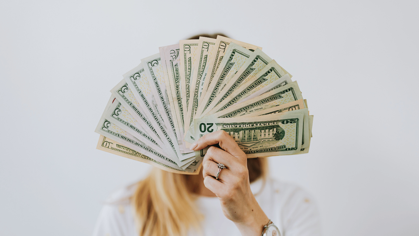 Person holding a fan of U.S. dollar bills, representing business earnings and cash flow Person holding a fan of U.S. dollar bills, representing business earnings and cash flow